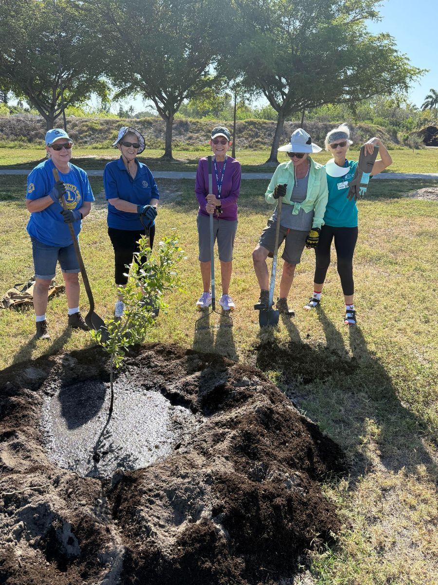 A group of people are standing next to a pile of dirt.
