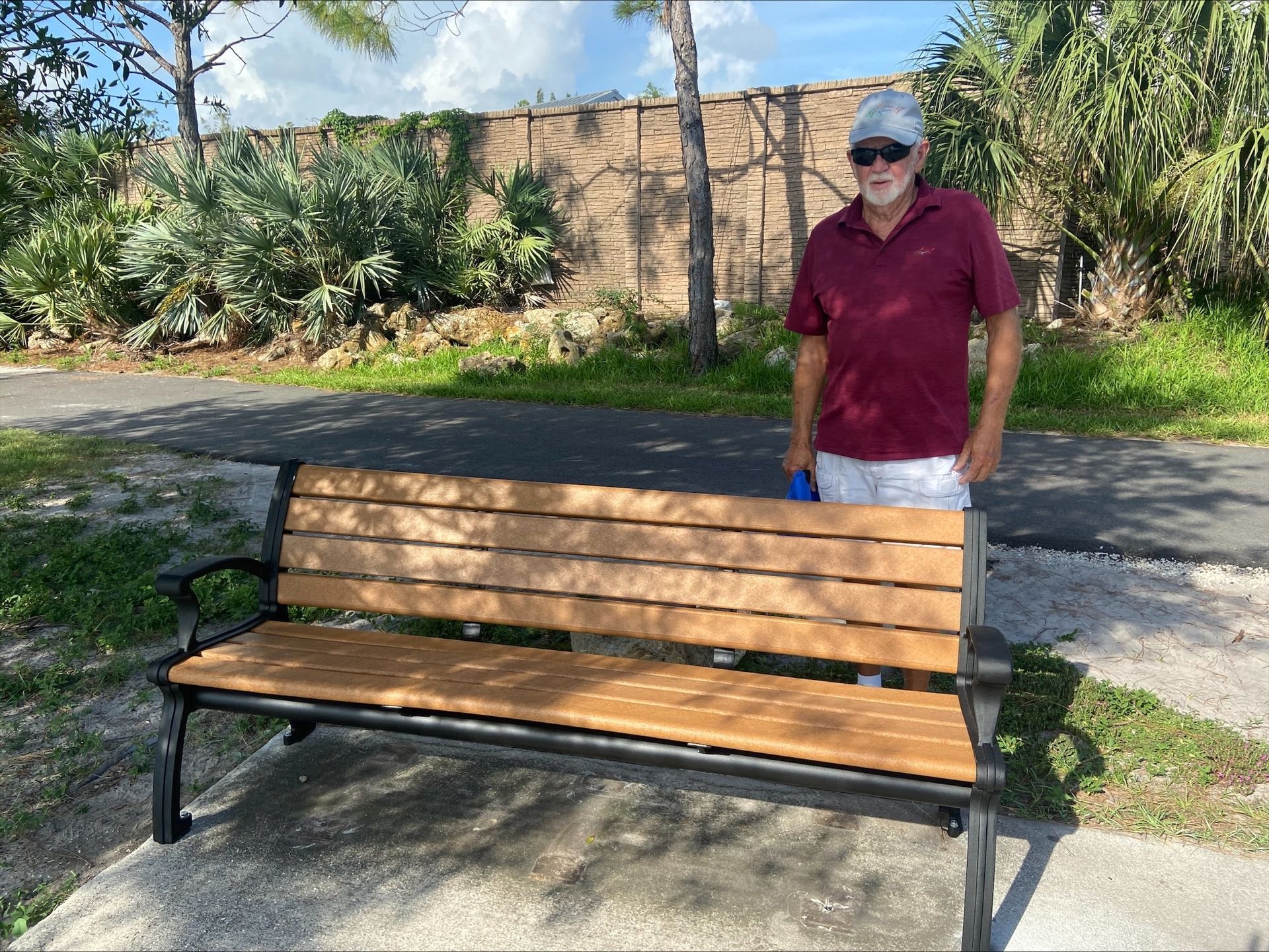 A man is standing next to a wooden park bench.
