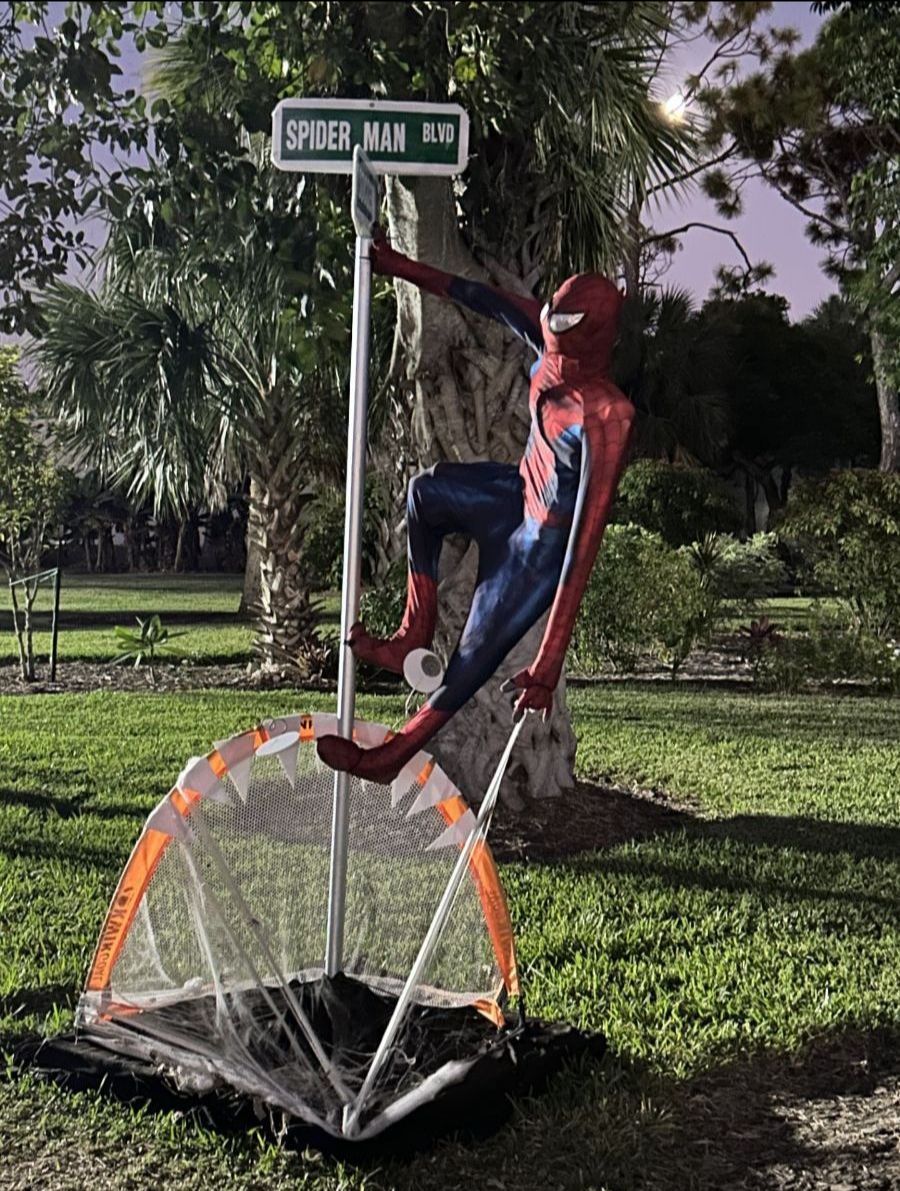 Spider-Man posing on a street sign that says