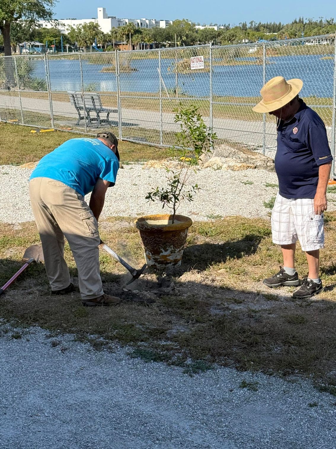 Two men are digging in the dirt in a park.