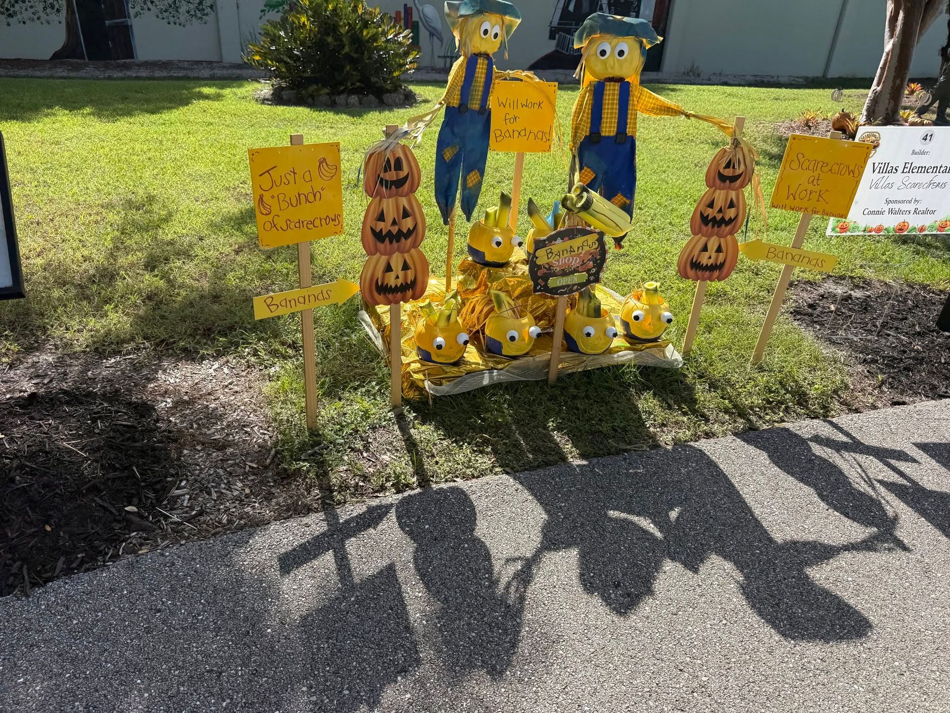 Halloween lawn display with painted wooden figures and pumpkin decorations on a sunny front yard lawn