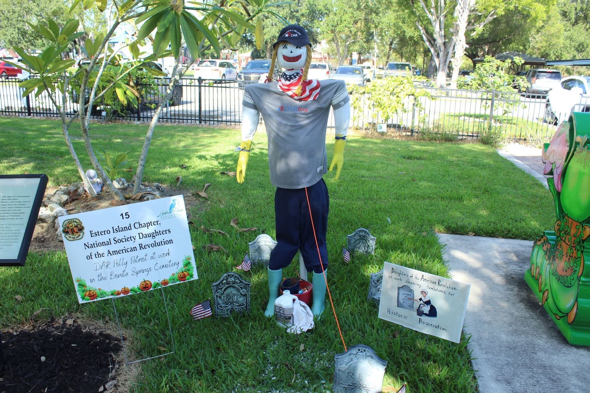 Halloween yard display with a scary gray zombie figure, signs, skulls, and pumpkins on a lawn
