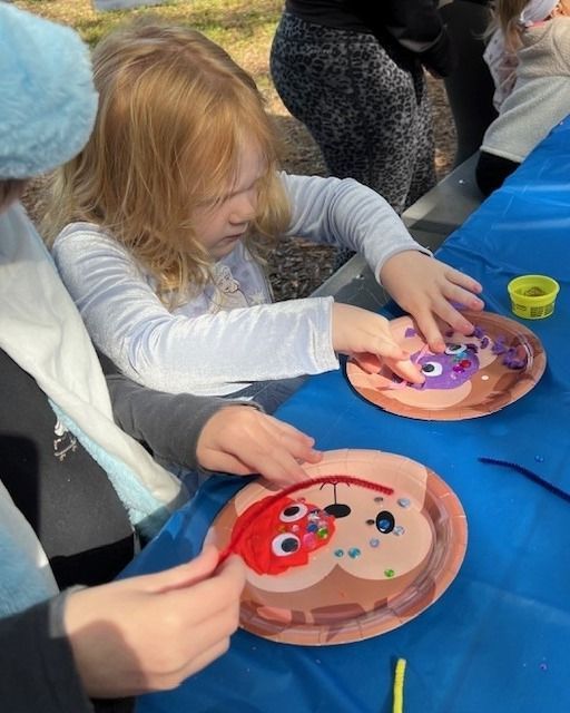 A little girl is painting a face on a paper plate