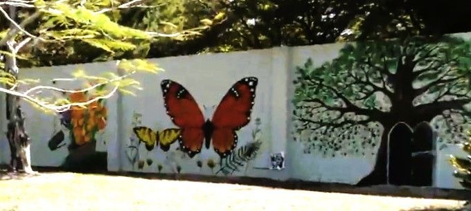 A wall with a butterfly and a tree painted on it