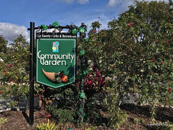 A sign for the community garden is surrounded by trees