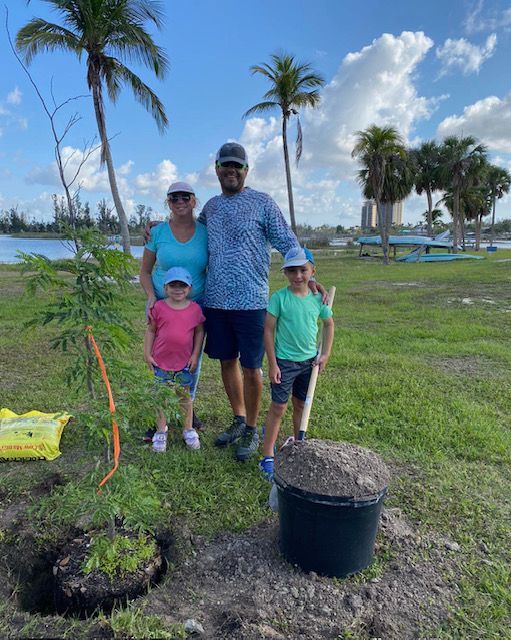 A family is standing next to a tree in a field.