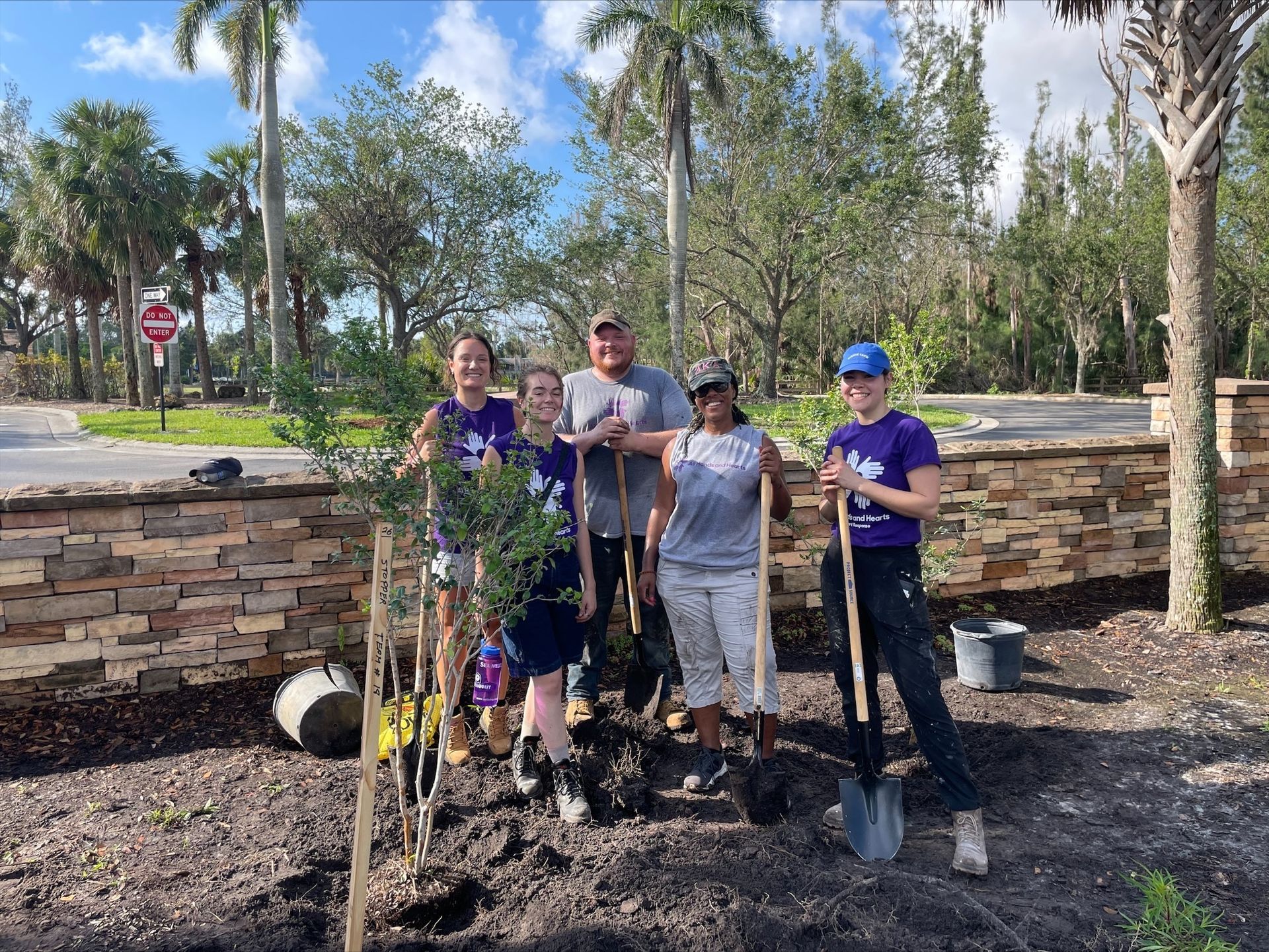 A group of people are standing next to each other holding shovels.