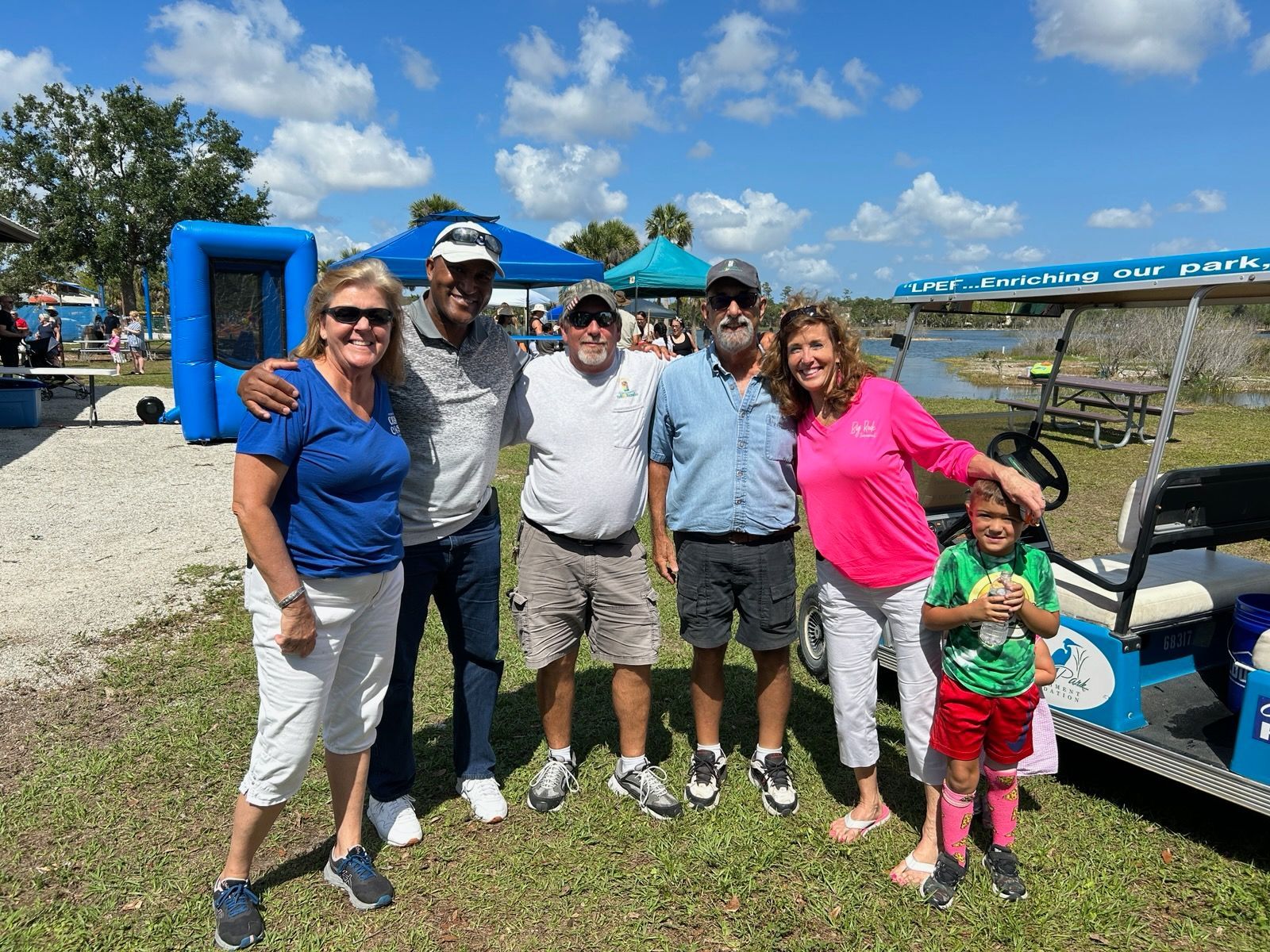 A group of people are posing for a picture in front of a golf cart.