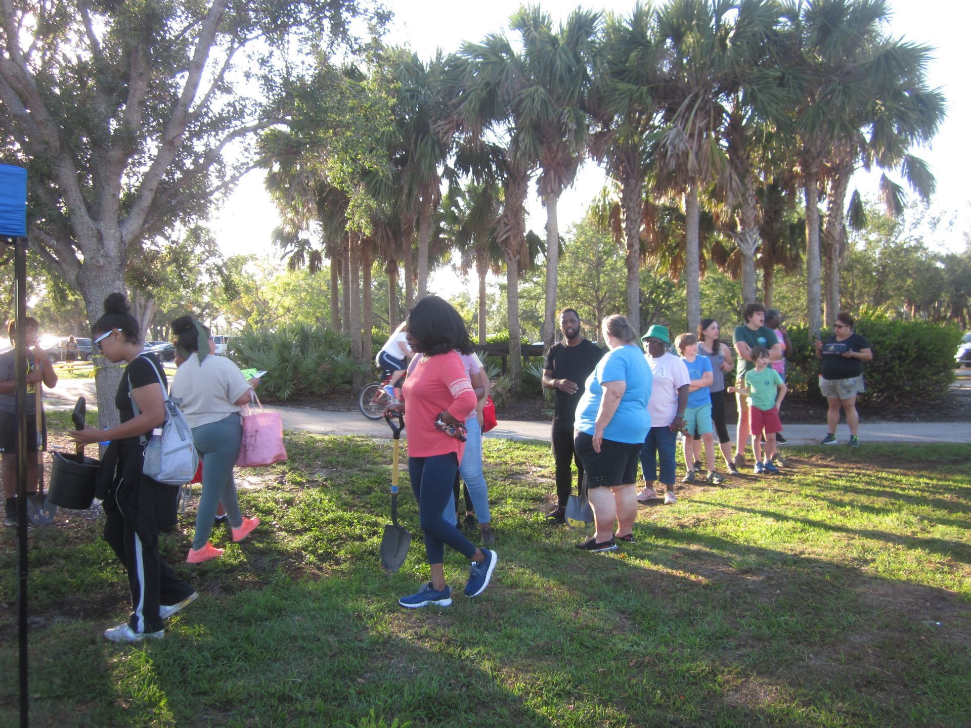 A group of people are standing in the grass in a park.