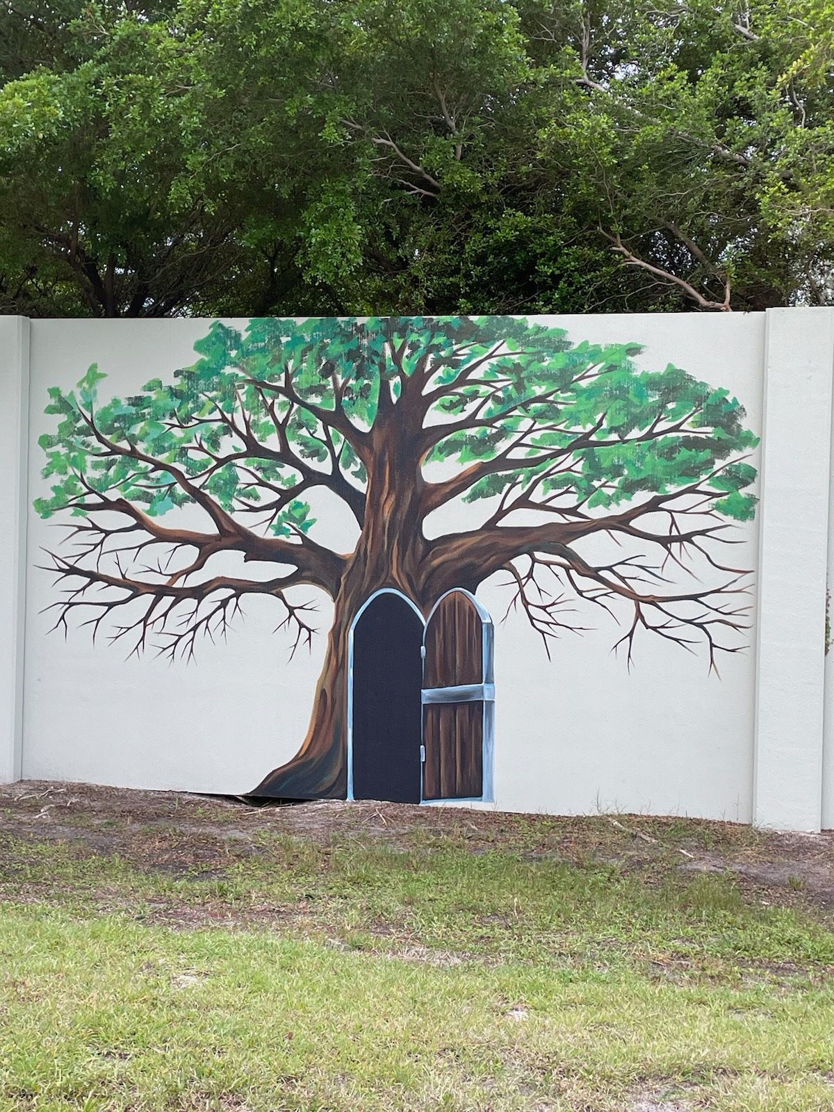 A painting of a tree with a door in the middle on a wall.