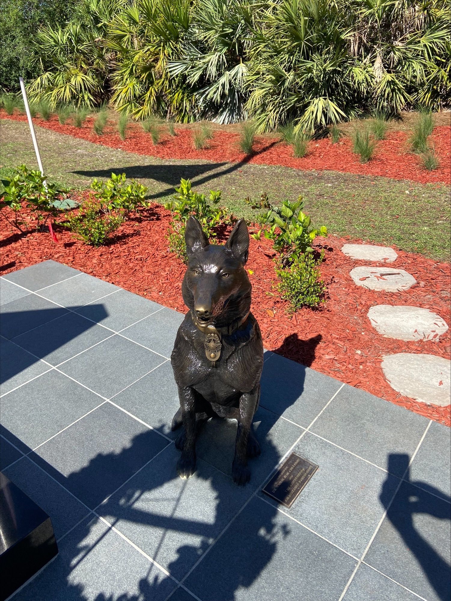 A statue of a dog is sitting on a tiled floor.
