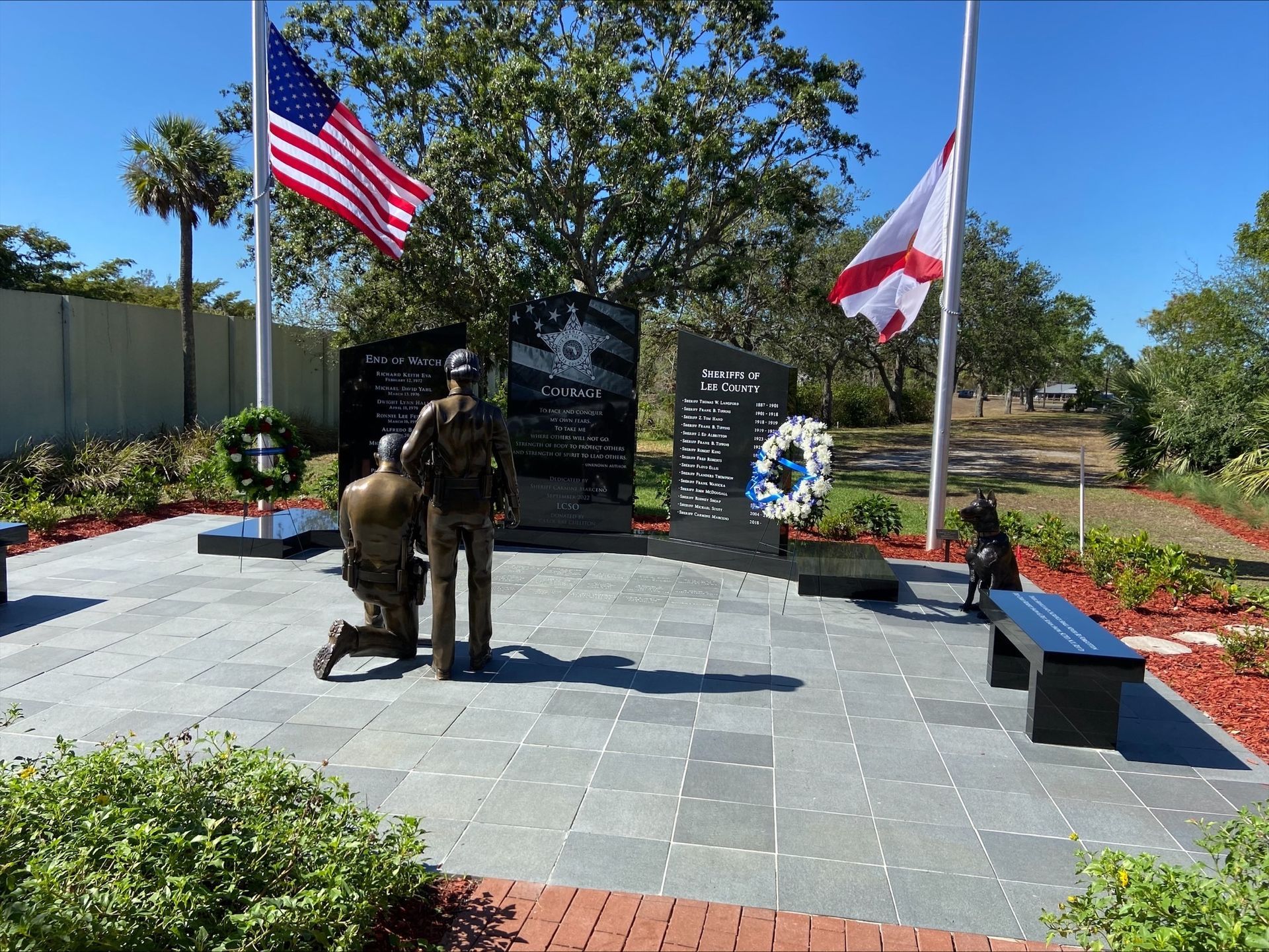 A statue of a man kneeling in front of an american flag