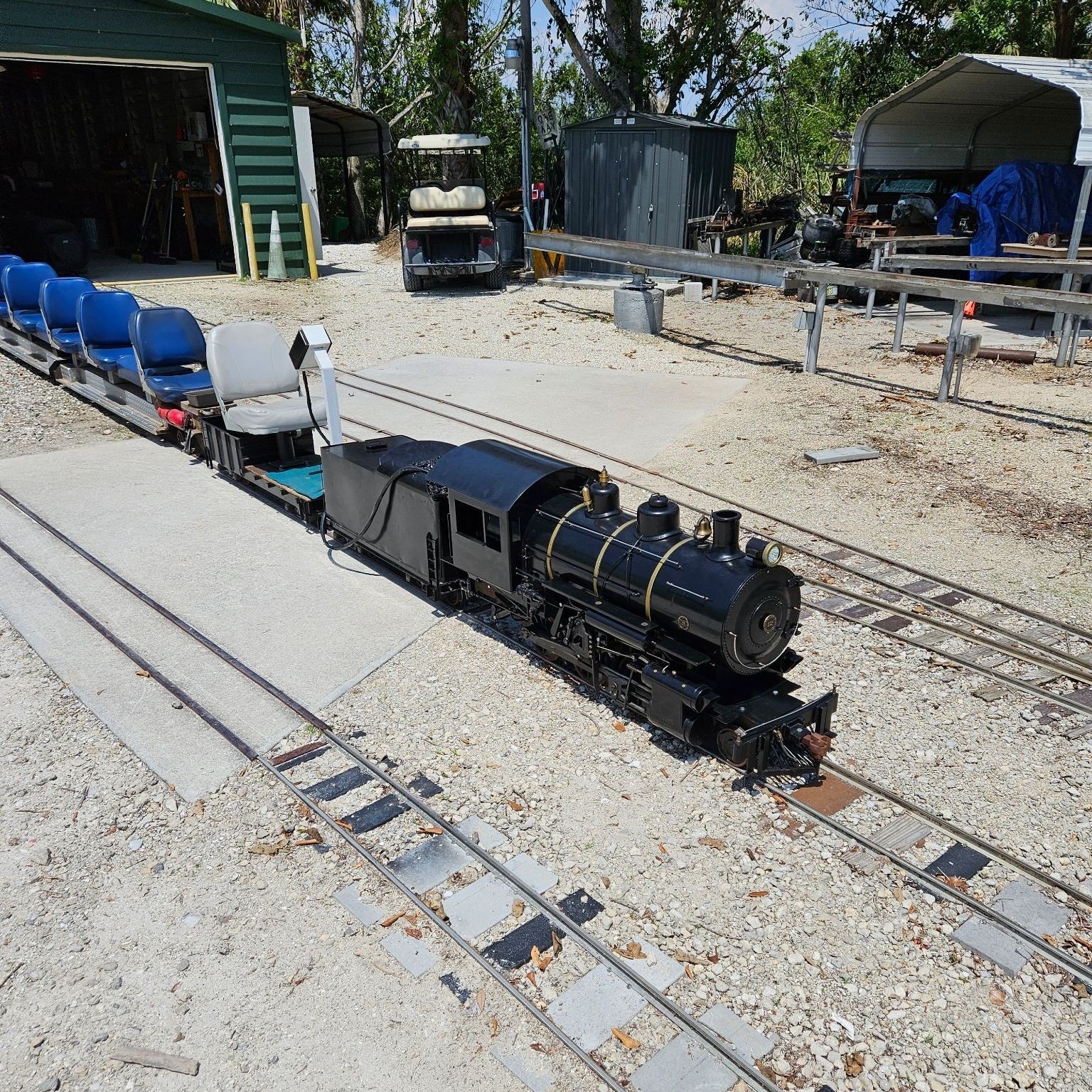 A model train is on the tracks in front of a shed