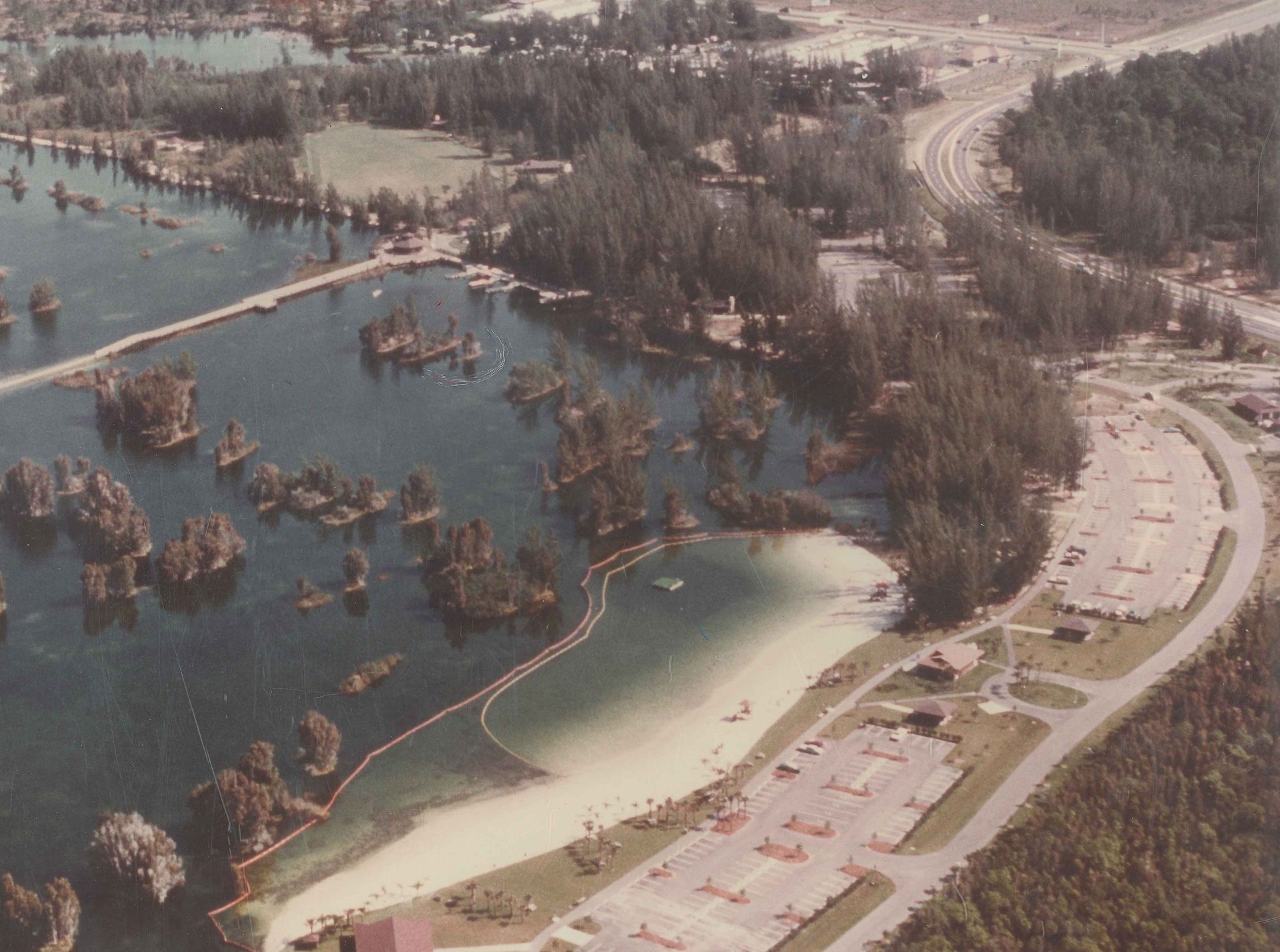 An aerial view of a lake surrounded by trees and parking lots