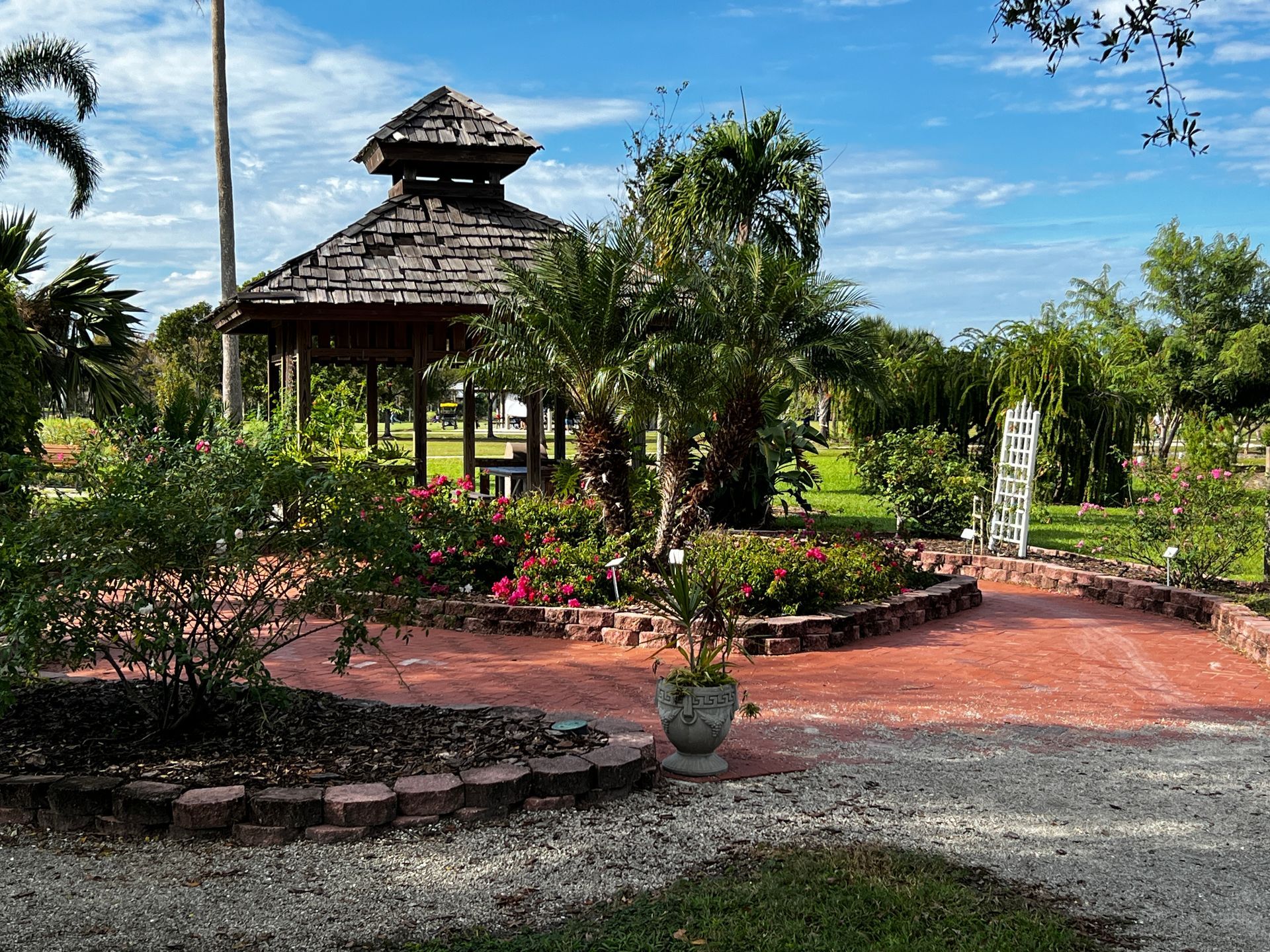 There is a gazebo in the middle of a garden surrounded by trees.