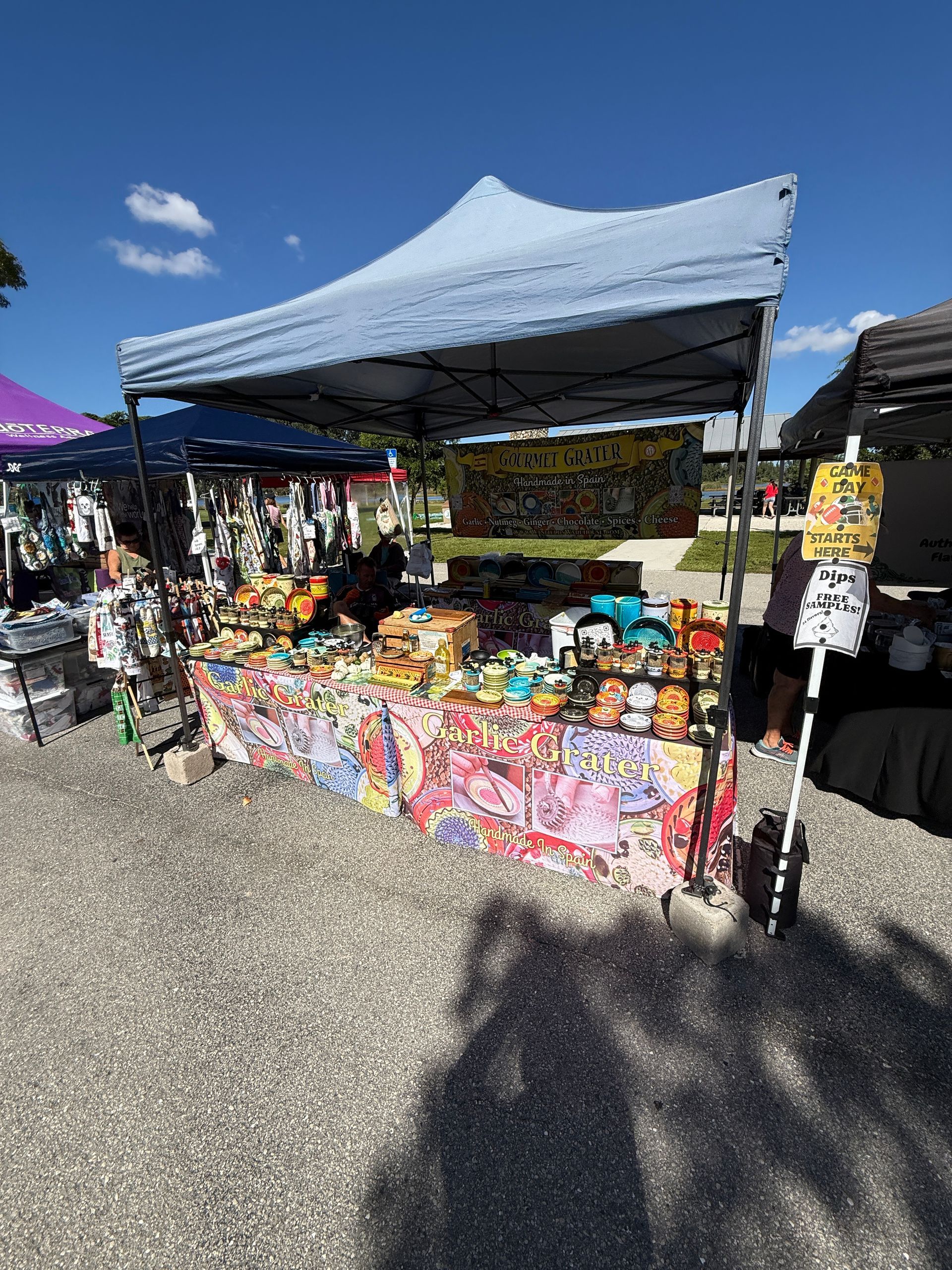 Outdoor market stall under a blue canopy selling colorful packaged snacks and goods.