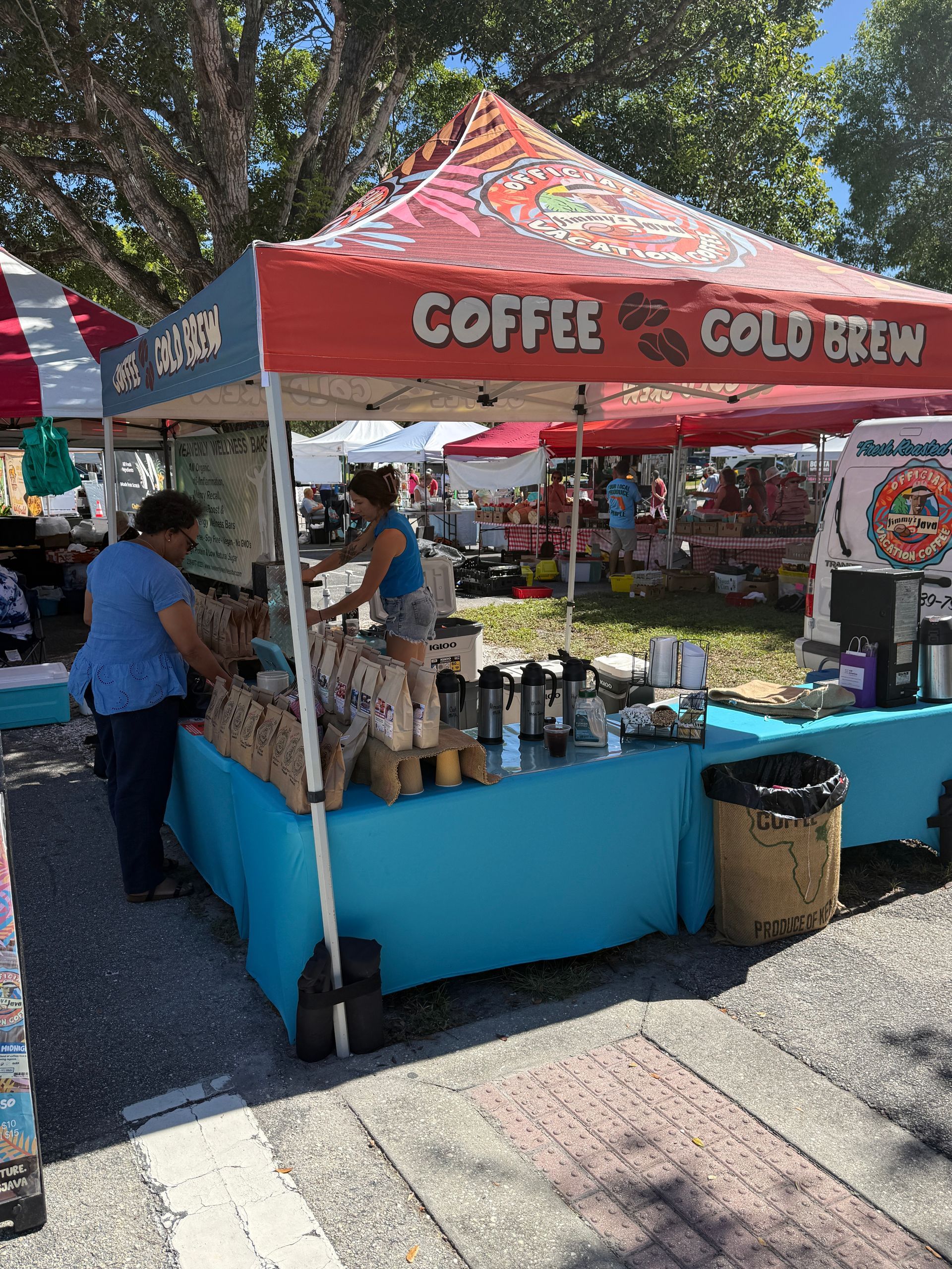 Outdoor coffee stand with a red canopy, blue counter, and customers ordering cold brew