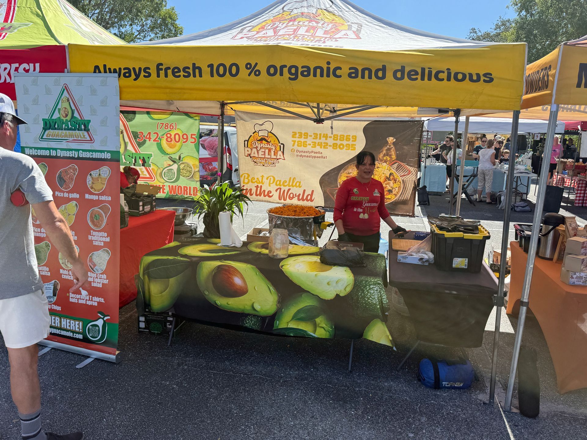 Orange juice stand under yellow canopy with “Fresh 100% organic and delicious” banner at an outdoor market