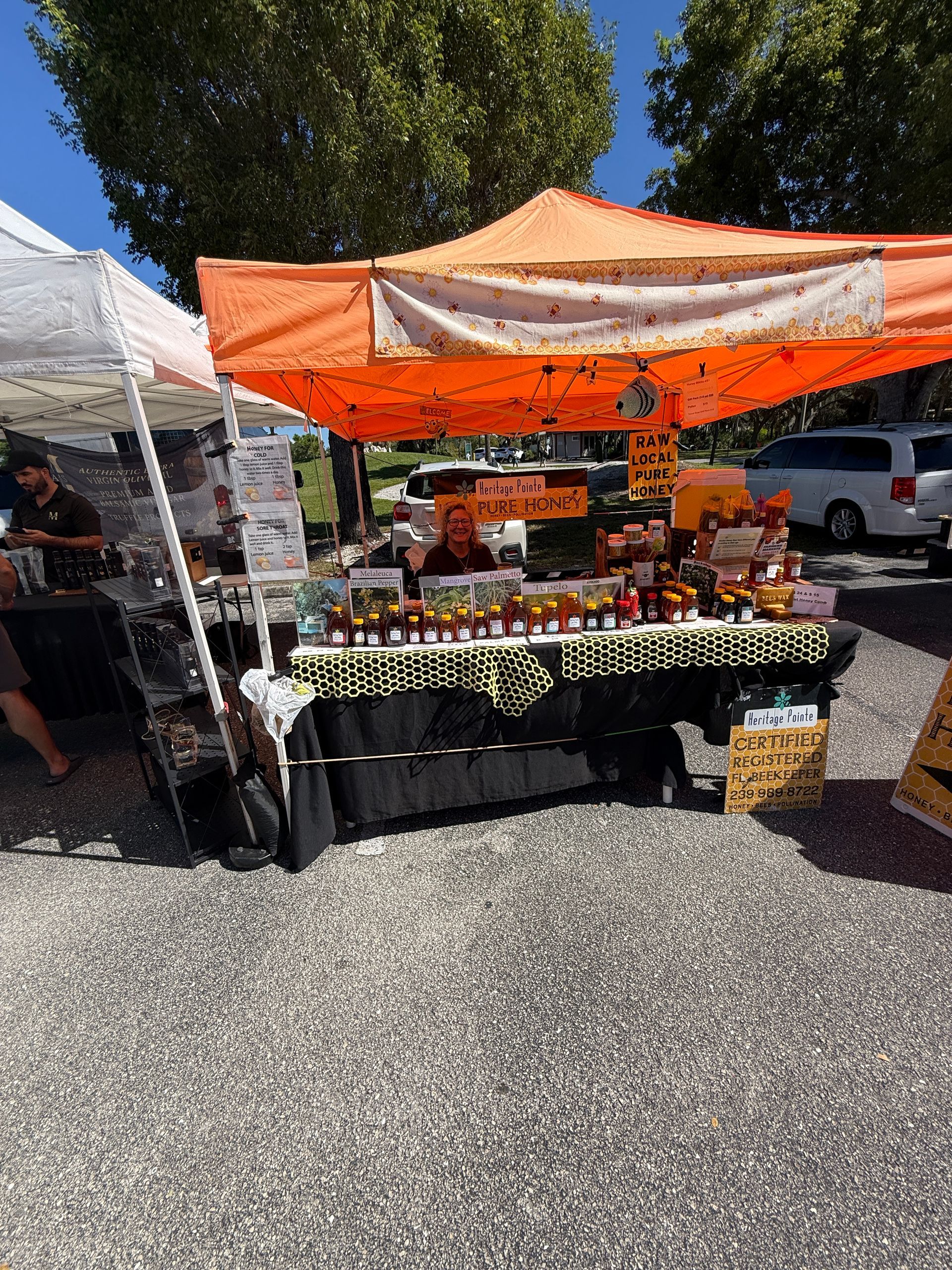 Outdoor market stall under orange canopy with plants and flowers displayed on tables
