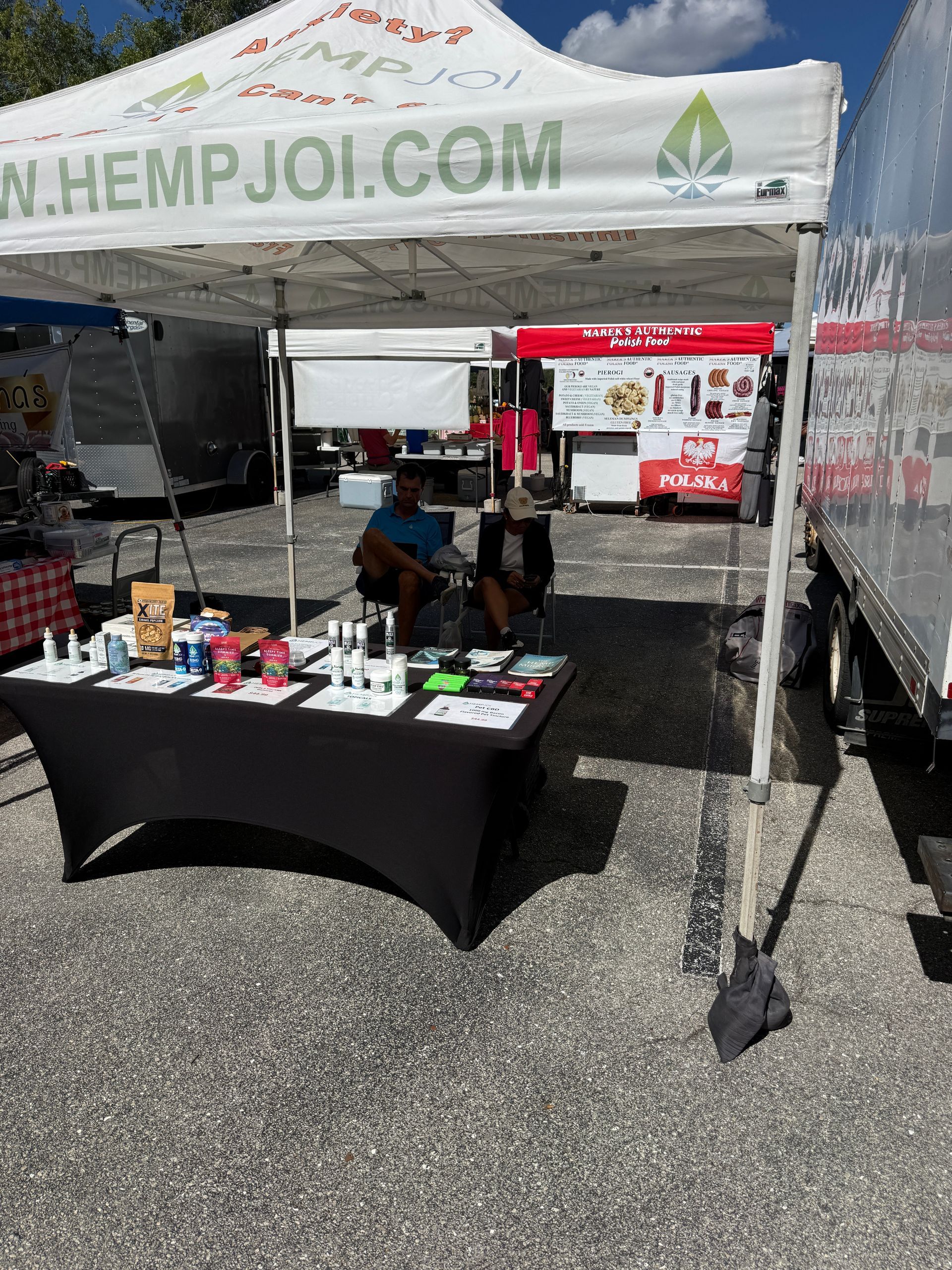 Hemp Joi vendor booth under white canopy with table displays at an outdoor event