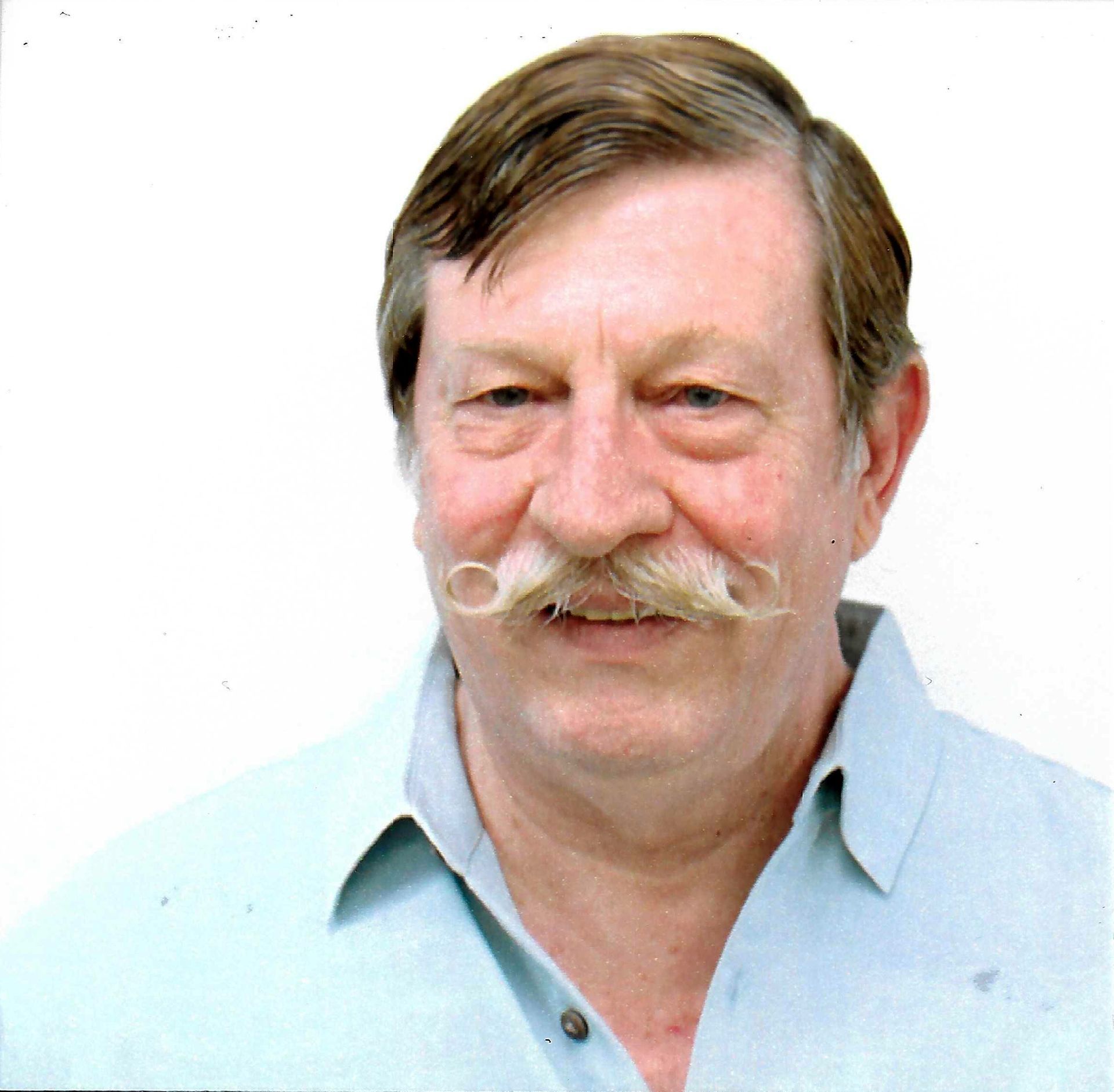 A man with a mustache is wearing a light blue shirt