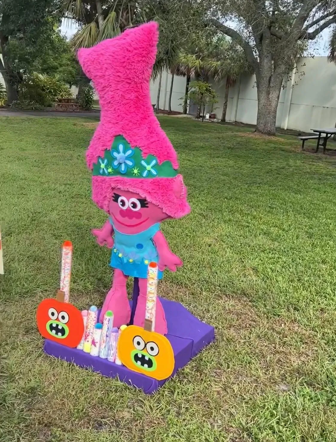 Troll Poppy Halloween display with pumpkins, candy, and a grassy outdoor setting.