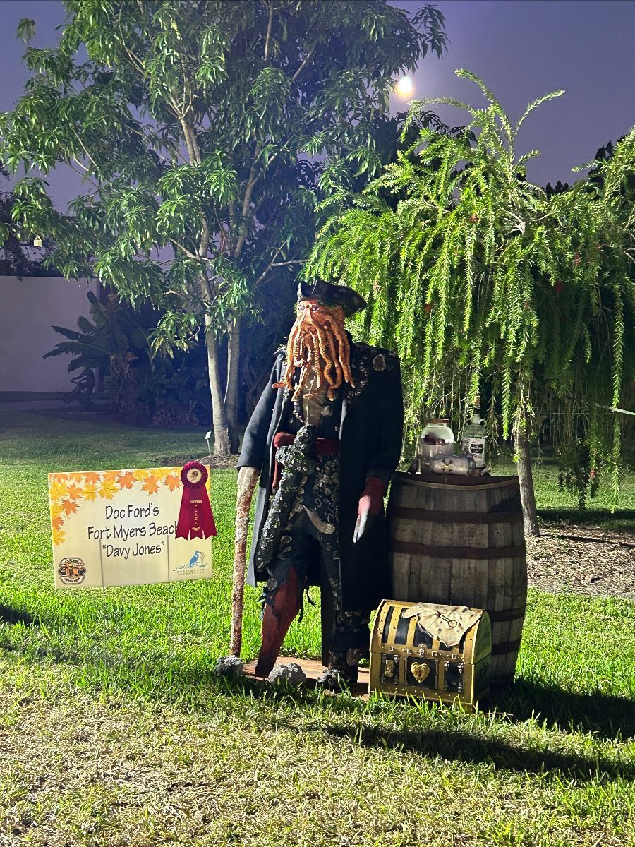 Pirate display in a yard at night with treasure chest, barrel, and sign: