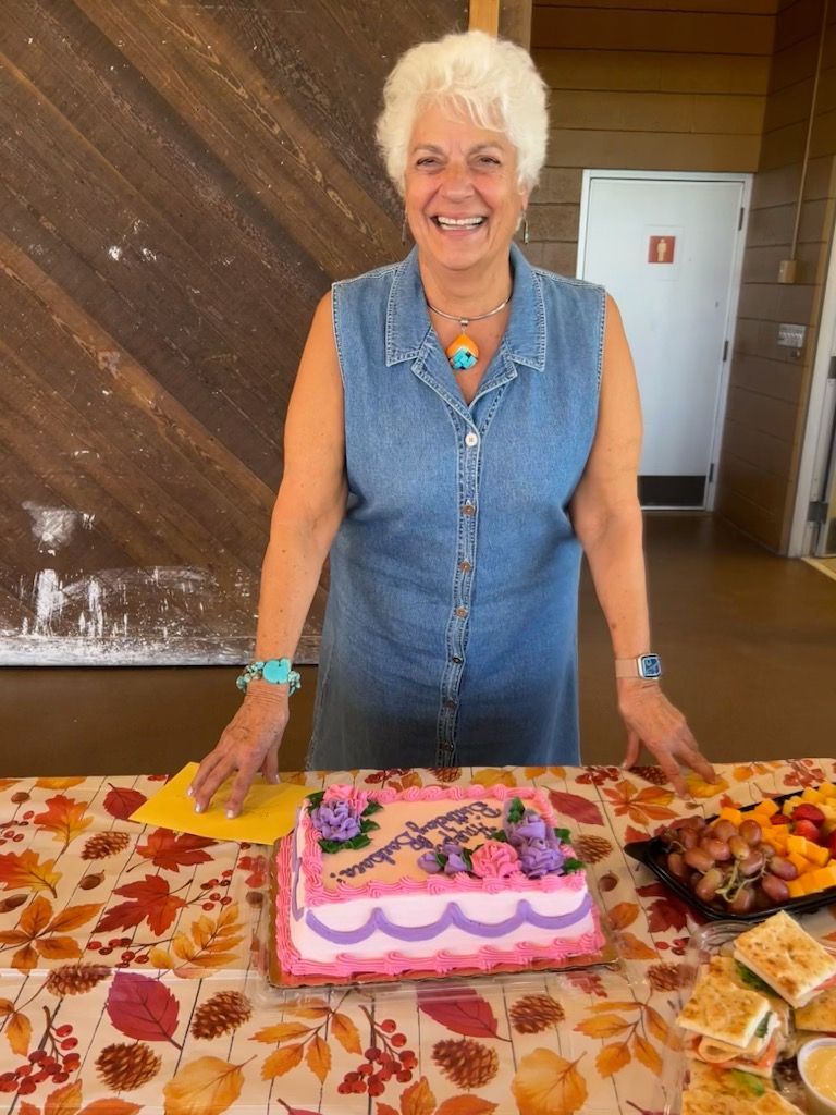 A woman is standing in front of a cake on a table.