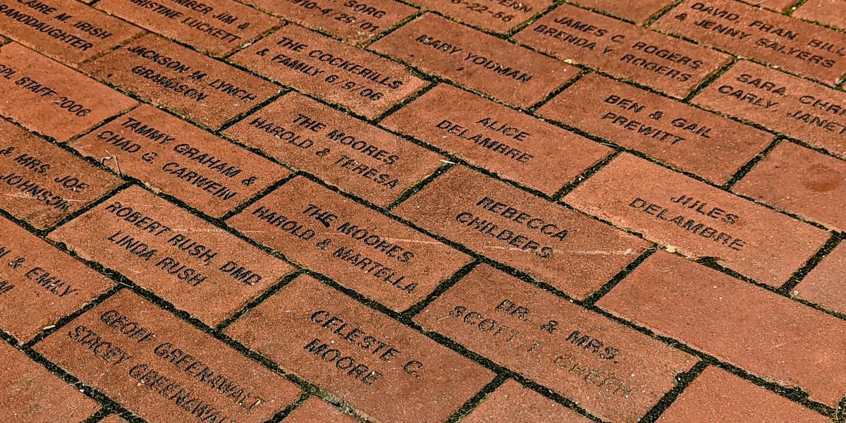 A bunch of bricks with names on them are laying on the ground.
