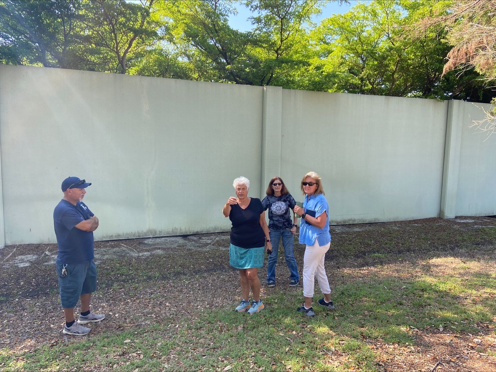 A group of people are standing in front of a white wall.