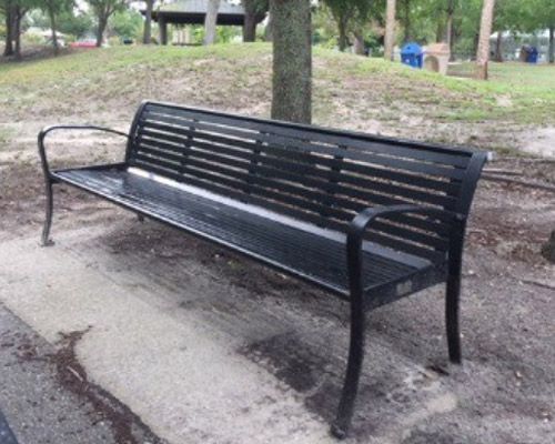A black park bench with a tree in the background