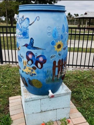 A large blue barrel is painted with butterflies and flowers