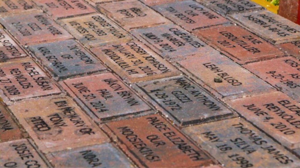 A row of bricks with names and dates on them