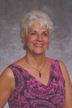 A woman in a pink and black dress is smiling for the camera.
