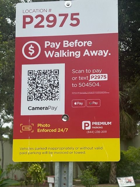 Parking sign with location code P2975, instructions to pay via QR code or text, and