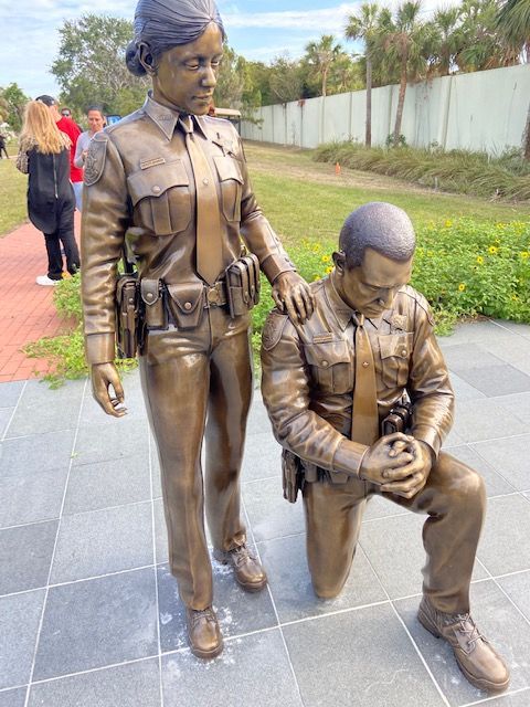 A statue of a police officer kneeling down next to another statue