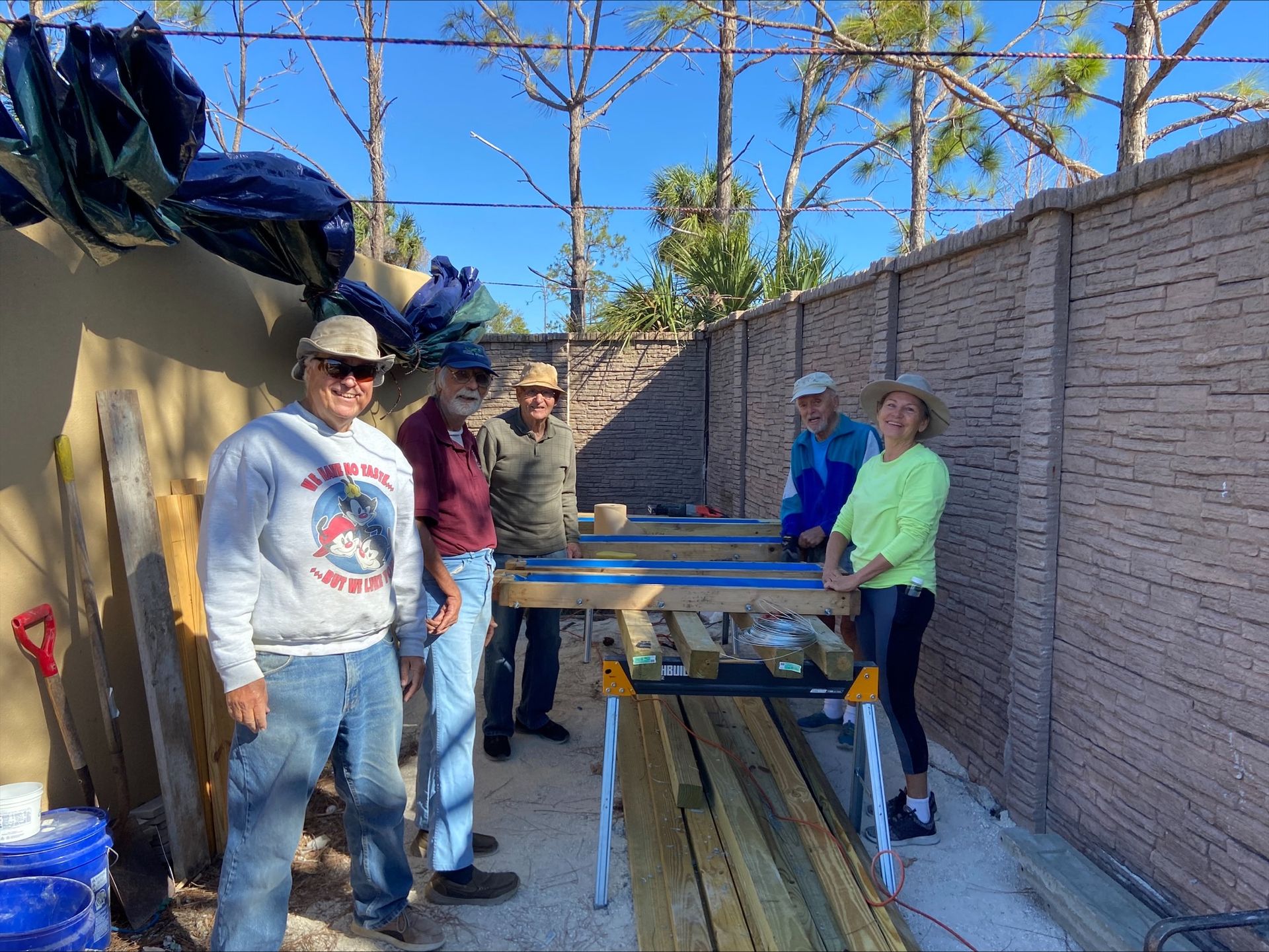 A group of people are standing around a wooden table.