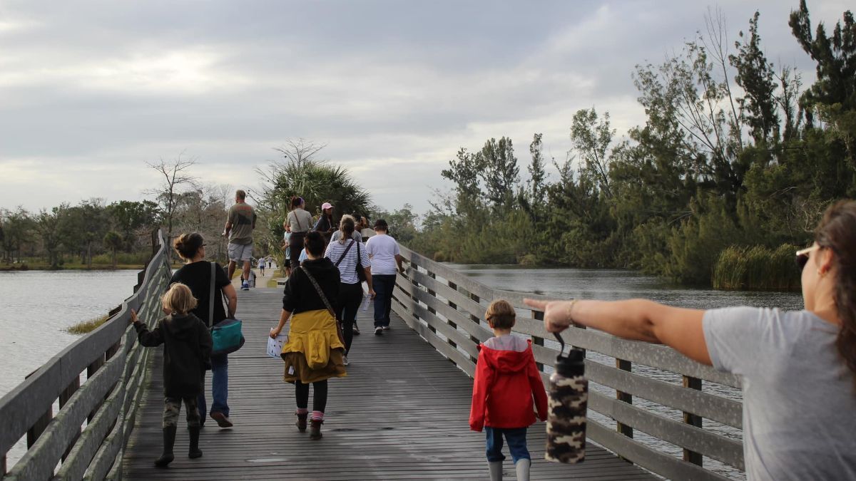 A group of people are walking across a wooden bridge over a body of water.