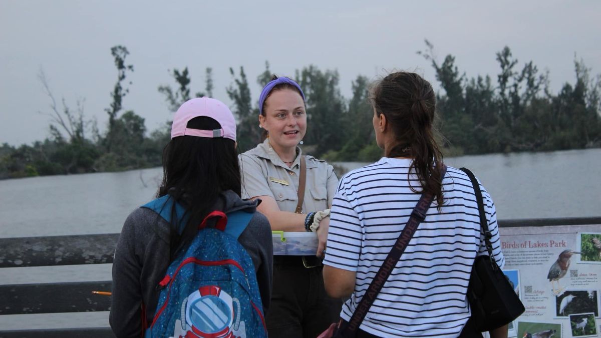 A man and two women are talking to each other on a bridge.