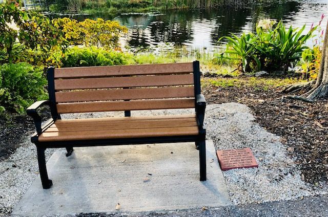 A wooden bench is sitting on a concrete platform in front of a lake.