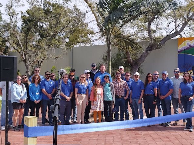 A group of people in blue shirts are standing in front of a blue ribbon.