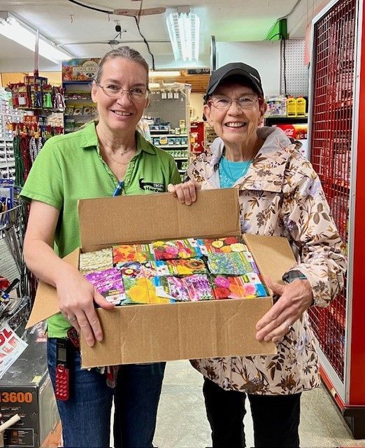 Two women are holding a box of seeds in a store