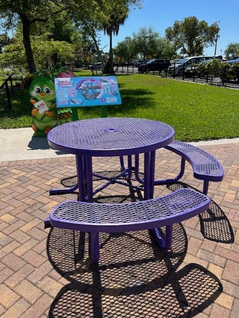 A purple picnic table sits on a brick sidewalk