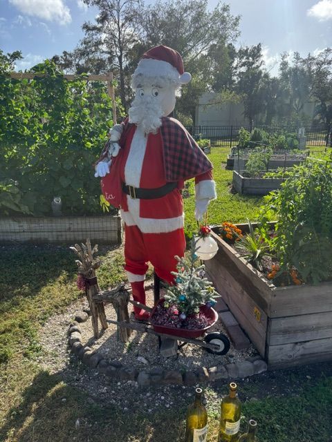 A statue of santa claus is standing in a garden.