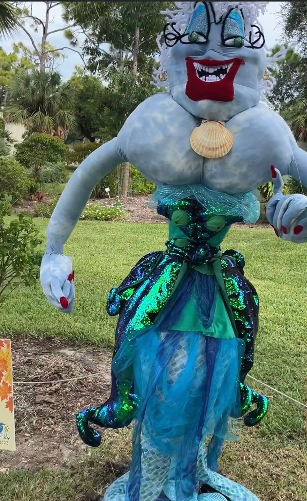 A scarecrow dressed as a mermaid is standing in the grass.