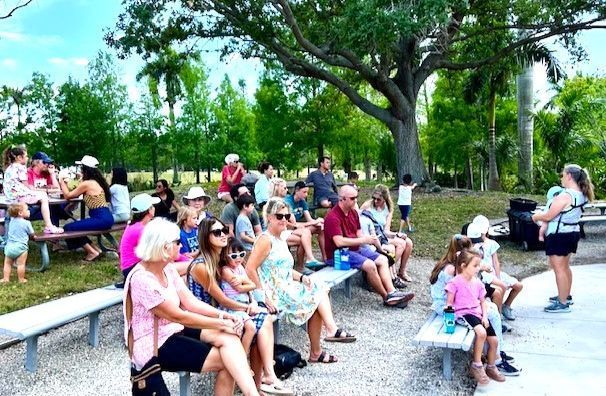 A group of people are sitting on benches in a park.
