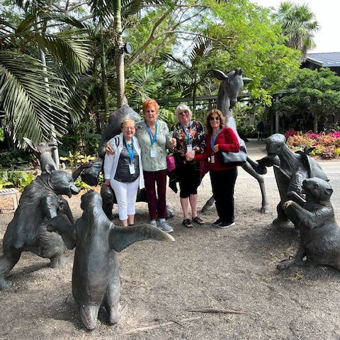 A group of women are posing for a picture in front of a statue of animals.