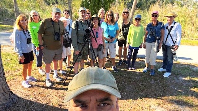 A man is taking a selfie with a group of people standing around him.