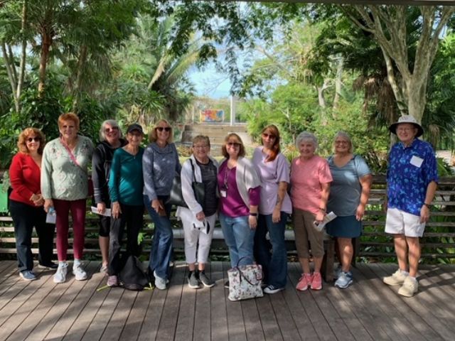 A group of people standing next to each other on a wooden deck.