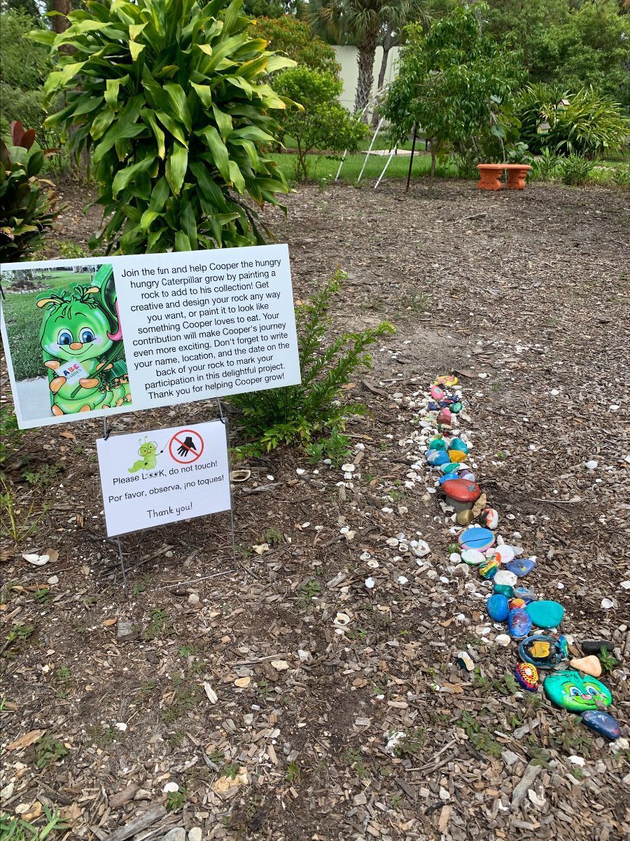 A row of rocks are lined up in a garden next to a sign.